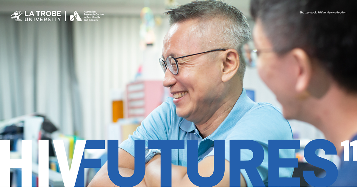 Older man with glasses and blue polo shirt in an office, smiling with another man, with text 'HIV FUTURES 11'