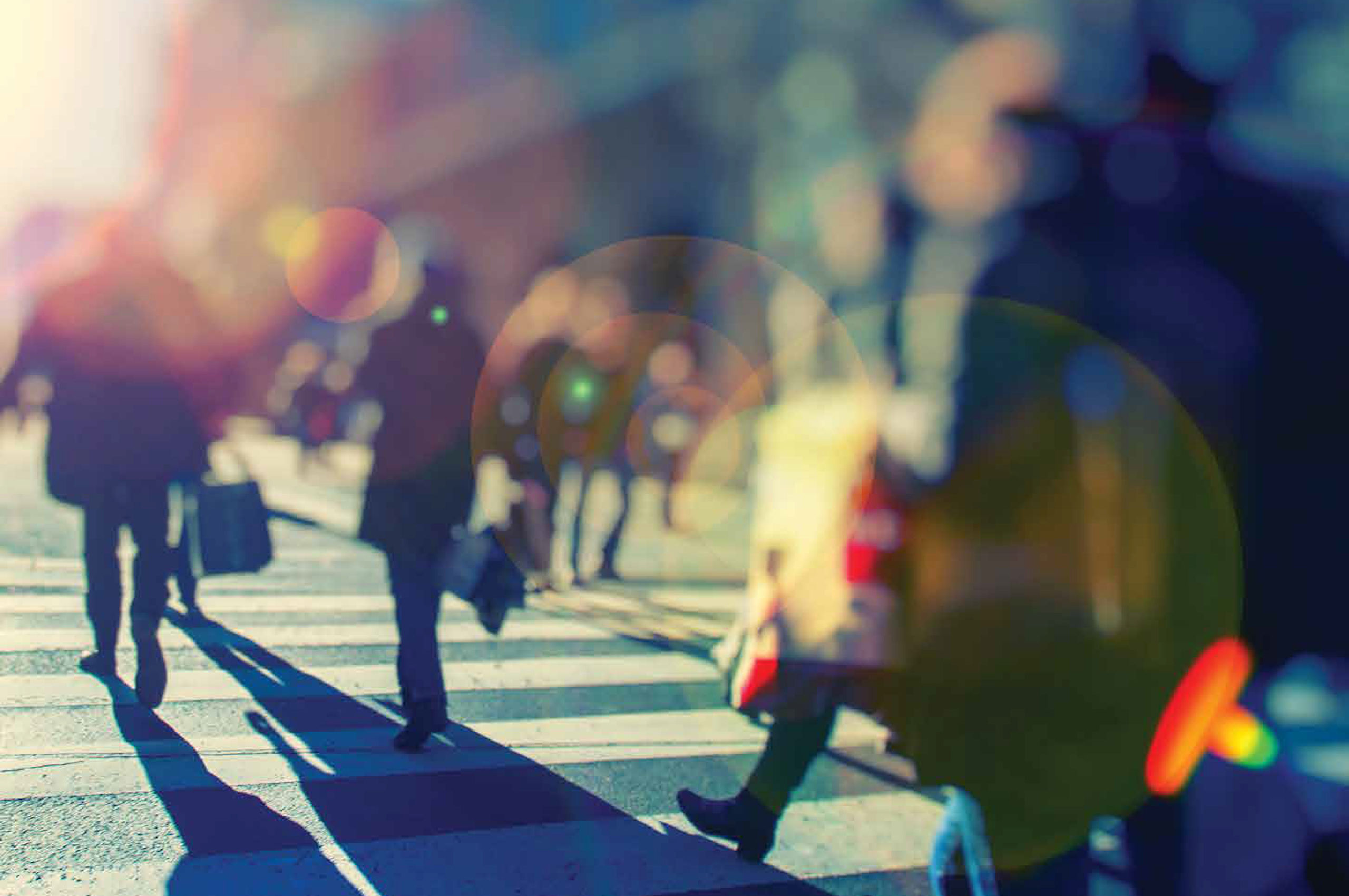 ARCSHS Annual Report 2017 High-contrast, partly blurred image of people walking across a zebra crossing with colourful lens flare