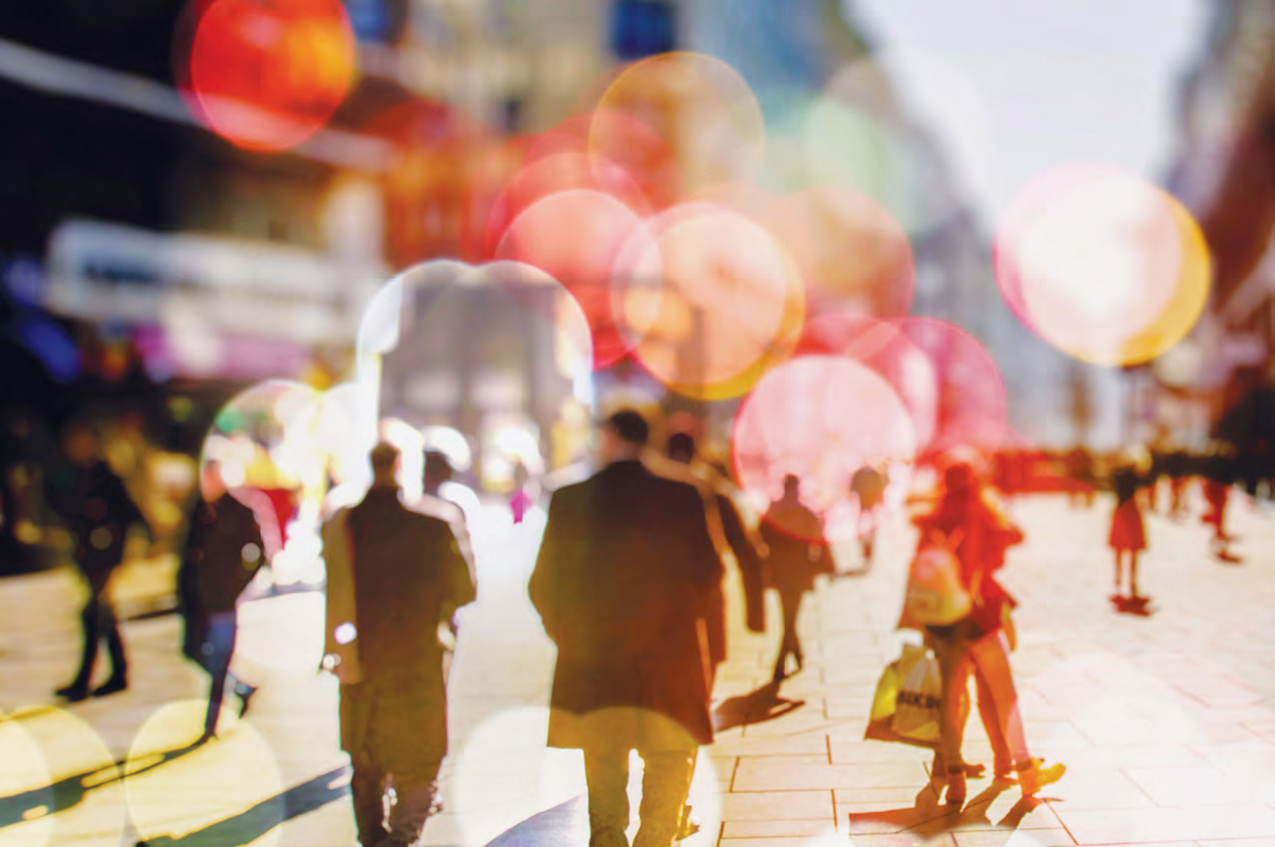 ARCSHS Annual Report 2018 Partly blurred image of people walking in a paved public square with brightly coloured lens flare