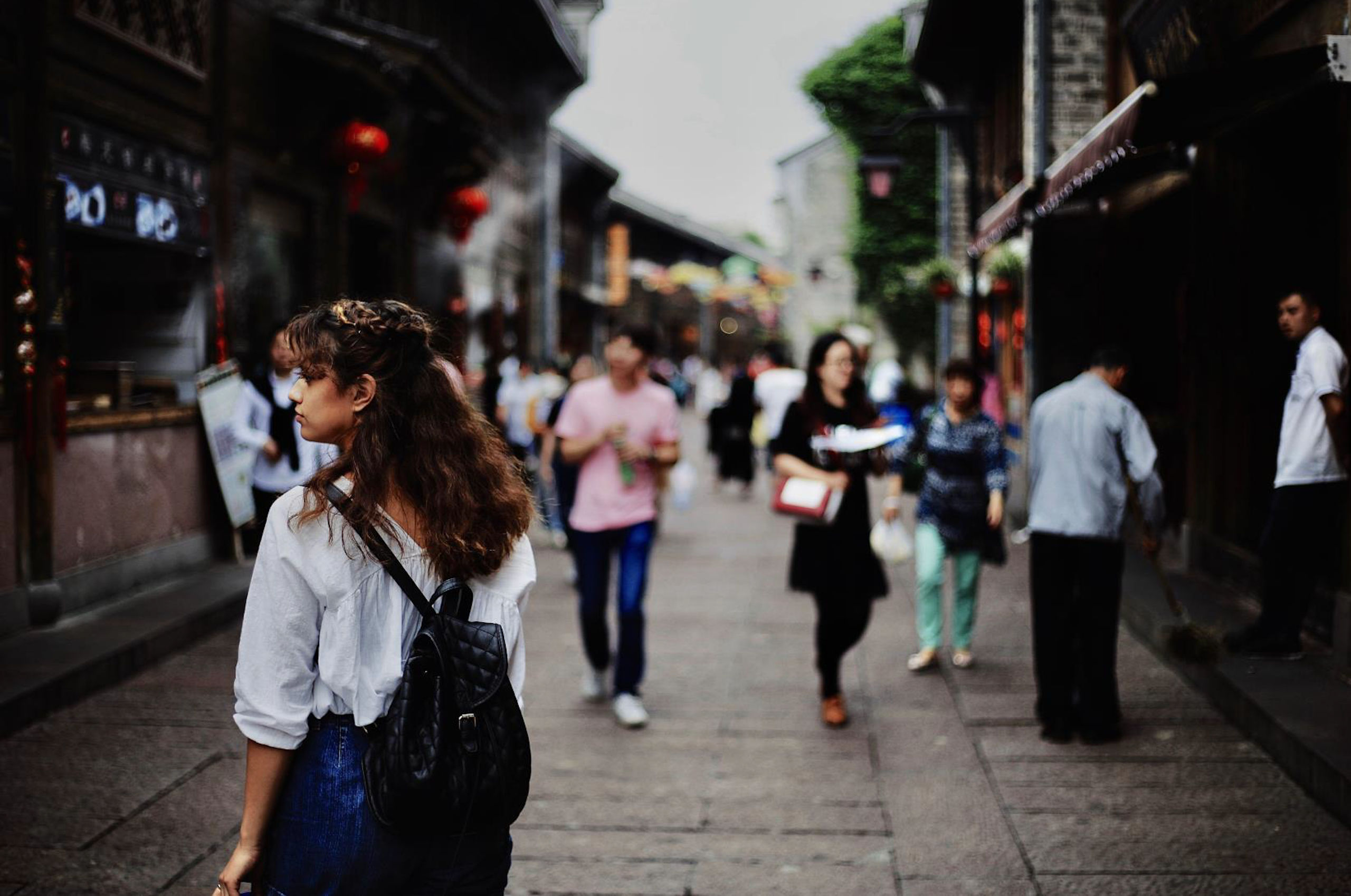 How do we value the role of community responses to HIV? People walk down an old-style narrow shopping street in an Asian city