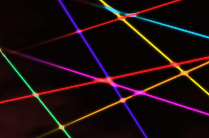Brightly coloured criss-crossing laser beams on a dark background