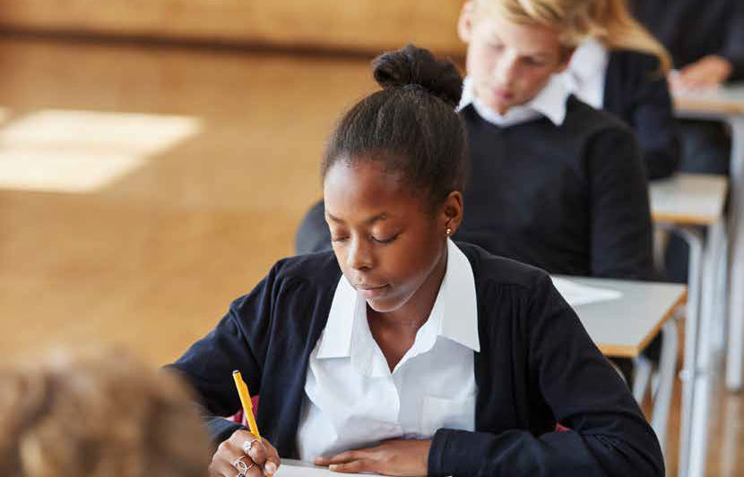Teenage girl sitting at a stand alone desk in a classroom setting