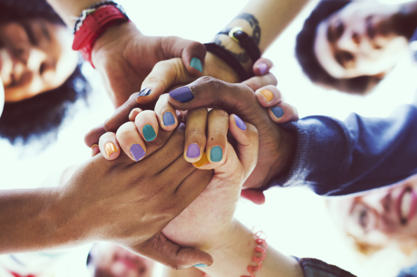 W3 project - Creating a set of evaluation indicators for peer-led work A group of diverse people in a circle with their hands joined in the centre, shot from below. The people have multi-coloured manicures, jewellery and tattoos.