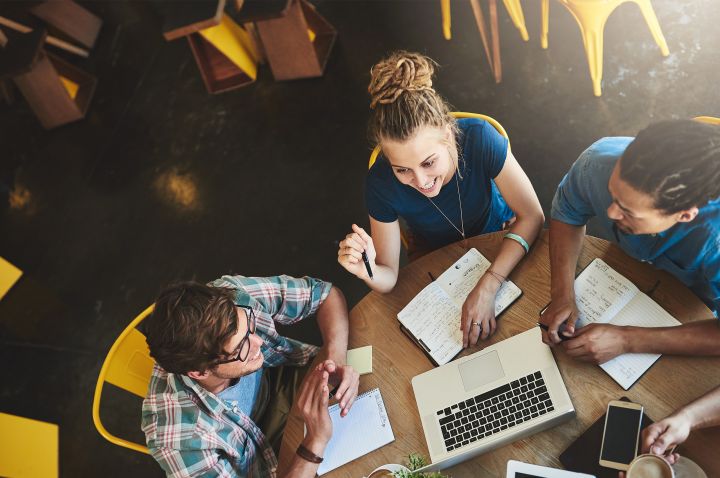 Three students sitting at a round table studying together